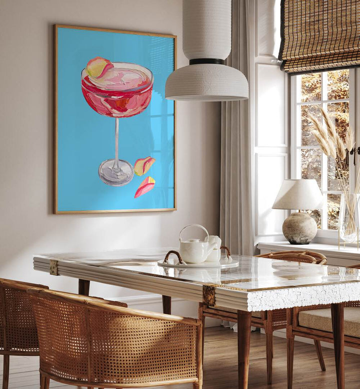 Sparkling Rose Gin Cocktail by Alice Straker Bar Posters Bar Art Prints in Oak Wood Plain Frame placed on a wall in a dining room area beside a window and behind a dining table