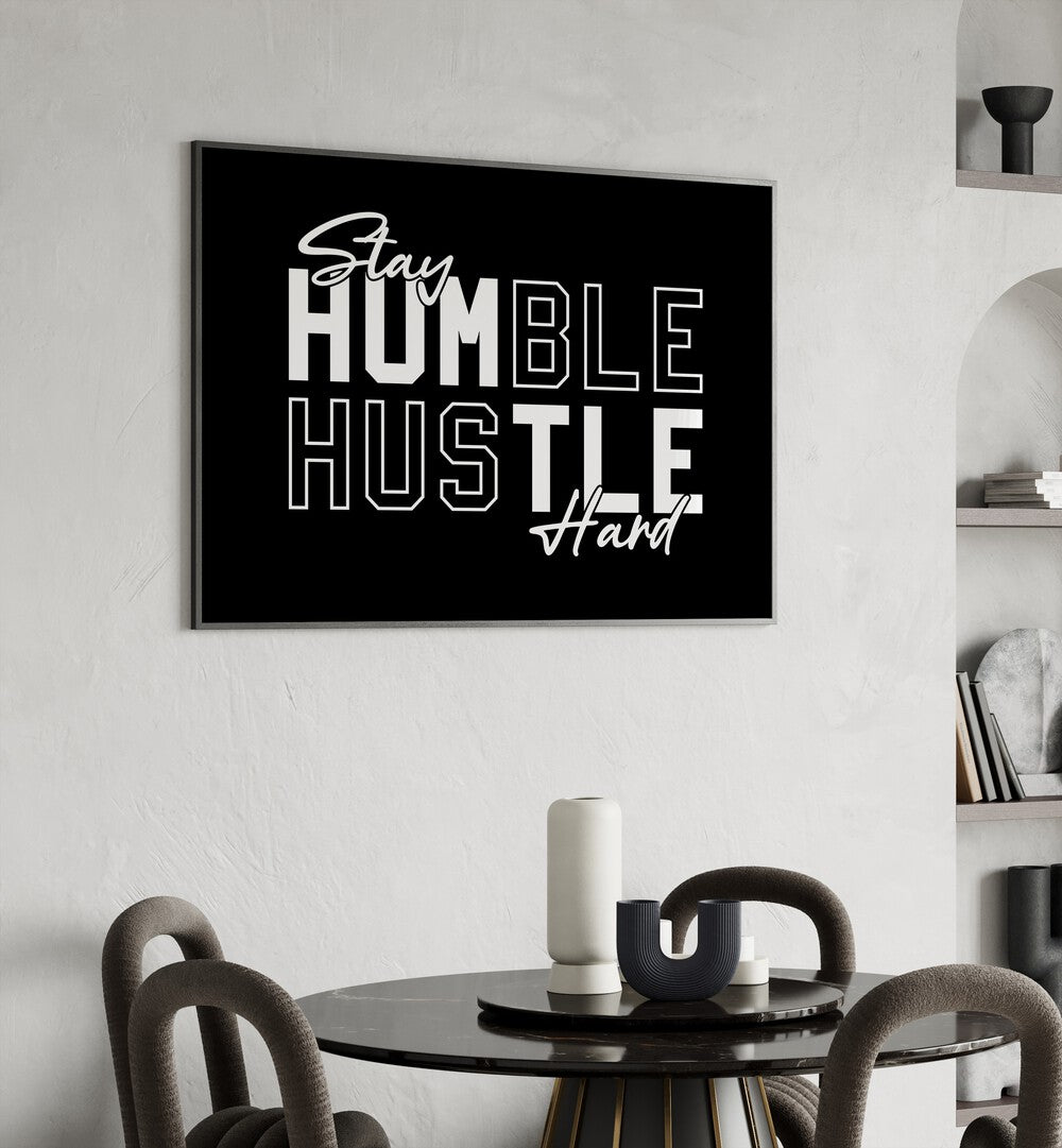 Stay Humble Hustle Harder iii Quotes and Typography Posters in Black Plain Frame placed on a wall behind a dining table