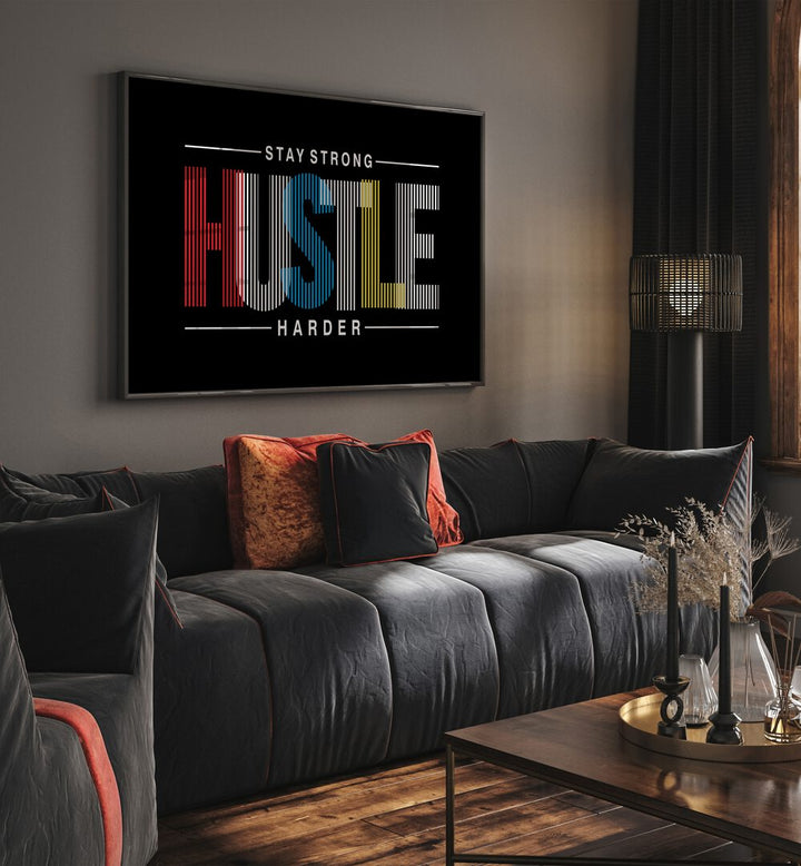 Stay Strong Hustle Harder Quotes and Typography Posters in Black Plain Frame placed on a wall in living room behind a sofa