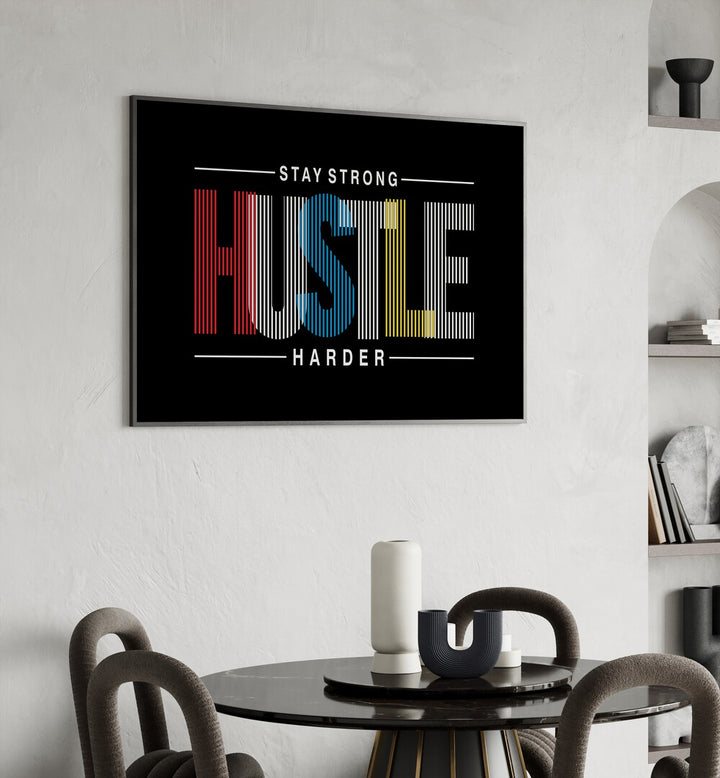 Stay Strong Hustle Harder Quotes and Typography Posters in Black Plain Frame placed on a wall in behind a dining table