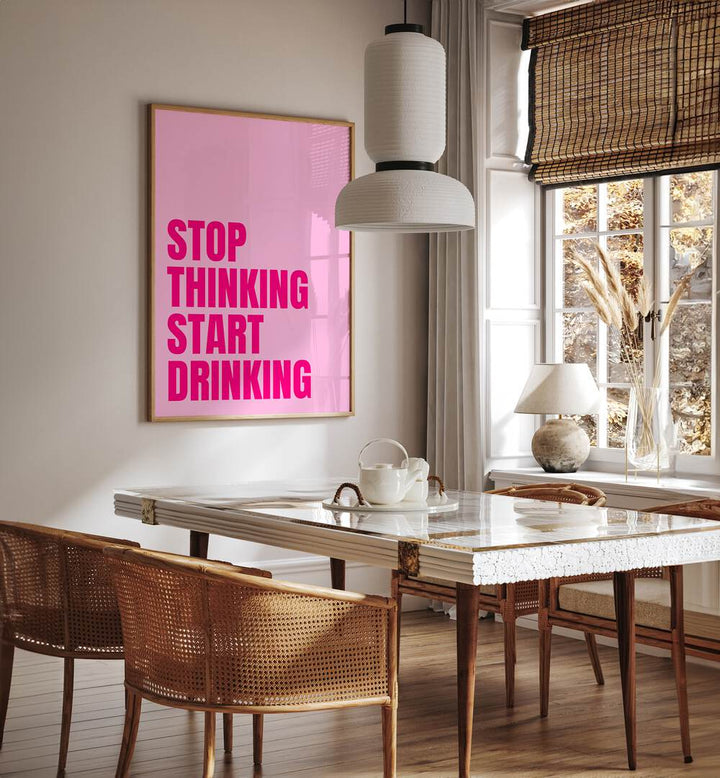 Stop Thinking Start Drinking by Athene Fritsch Quotes and Typography Posters in Oak Wood Plain Frame placed on a wall in a dining room area beside a window and behind a dining table