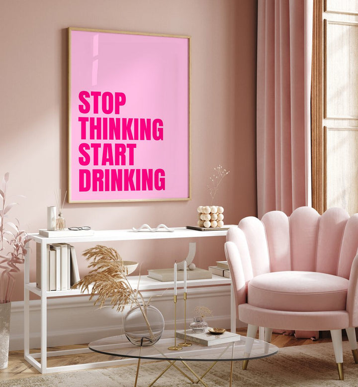 Stop Thinking Start Drinking by Athene Fritsch Quotes and Typography Posters in Oak Wood Plain Frame placed on a pink wall beside a window and behind a table