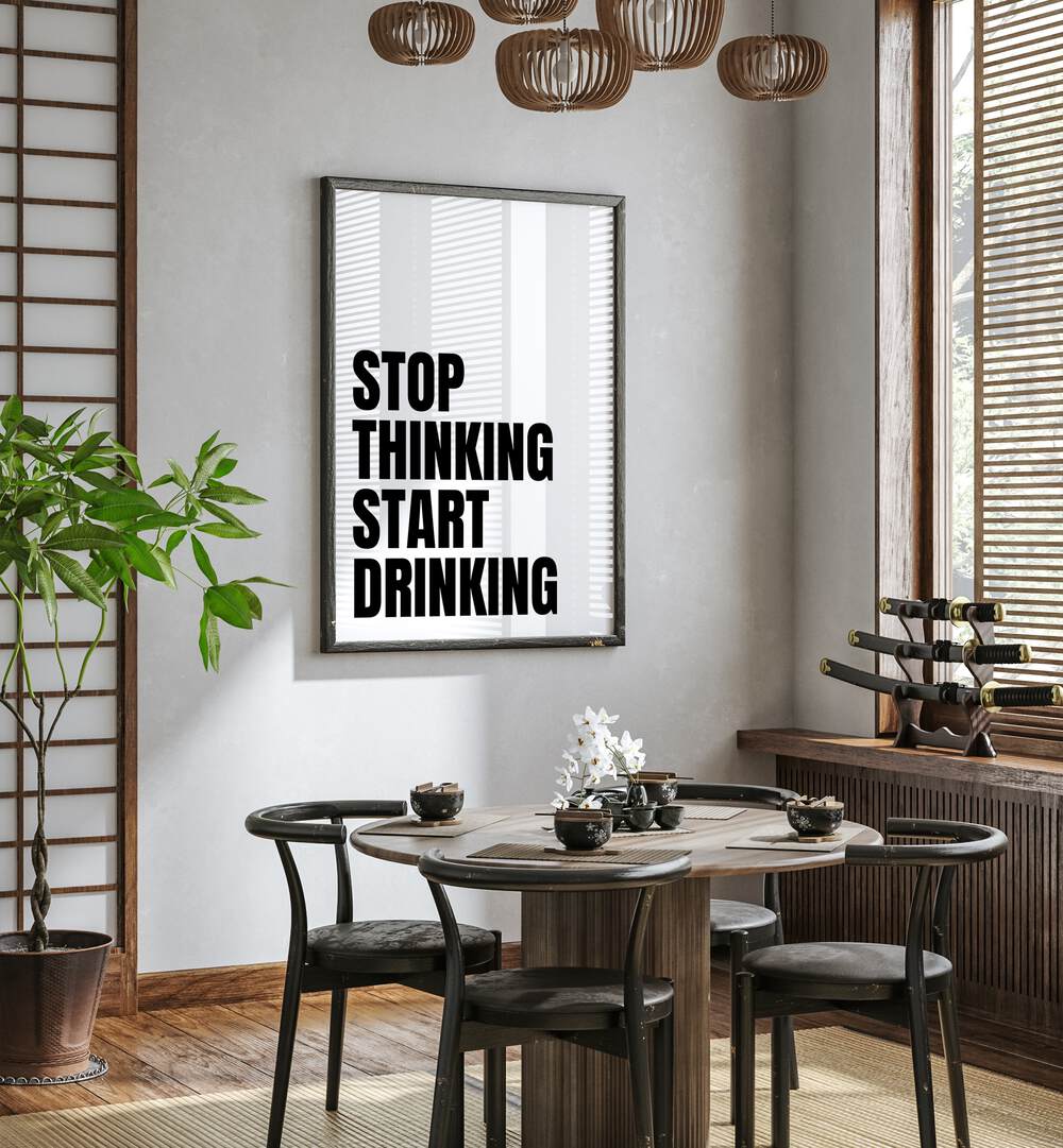 Stop Thinking Start Drinking ii by Athene Fritsch Quotes and Typography Posters in Black Plain Frame placed on a wall in a dining room area beside a window and behind a dining table