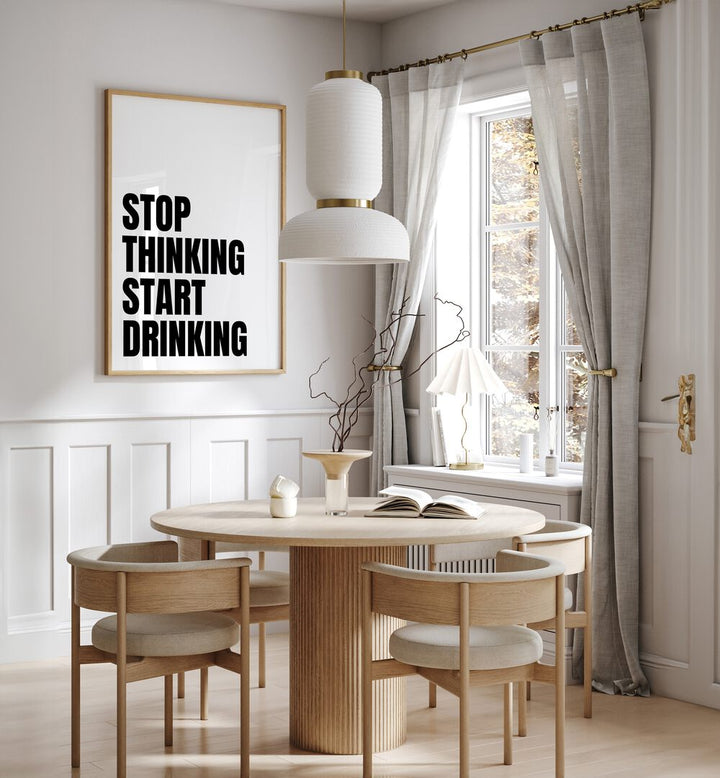 Stop Thinking Start Drinking ii by Athene Fritsch Quotes and Typography Posters in Oak Wood Plain Frame placed on a wall in a dining room area beside a window and behind a dining table