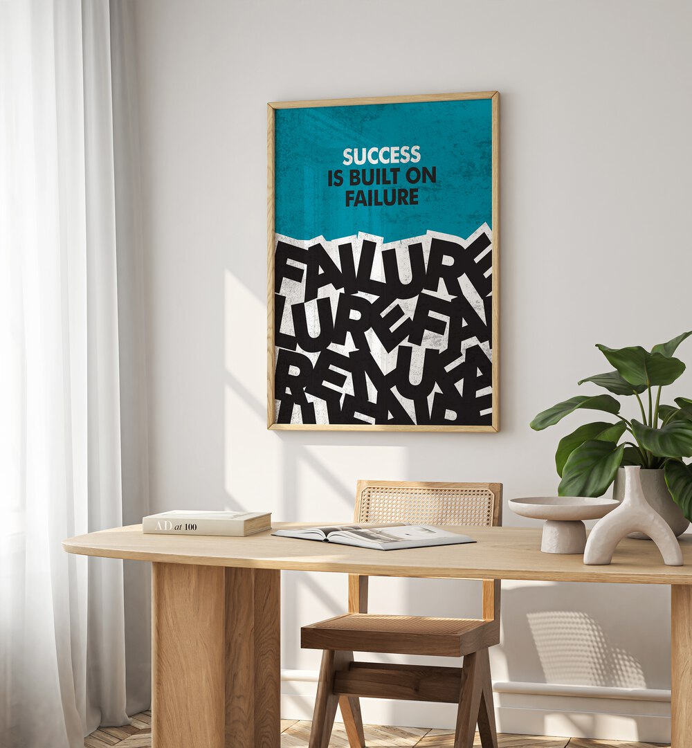 Success Is Built On Failure Quotes And Typography Posters in Oak Wood Plain Frame placed on a White Colored Wall near a Study Table in a Workspace in the Drawing Room