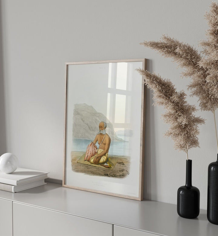 The Secret Prayer Artwork Indian Art Painting Artwork in plain white frame on a table next to a book