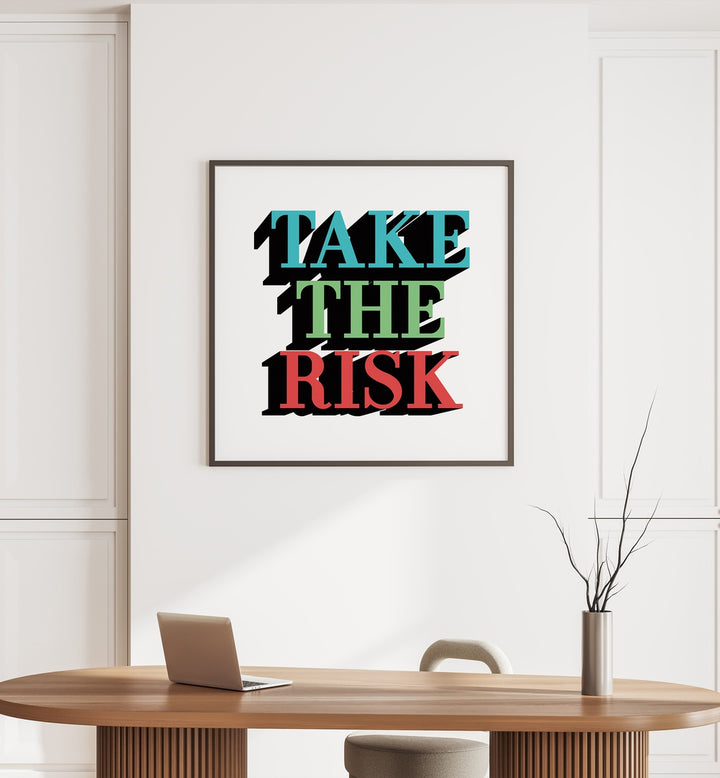 Take the Risk Quotes and Typography Posters in Black Plain Frame placed on a wall behind a table