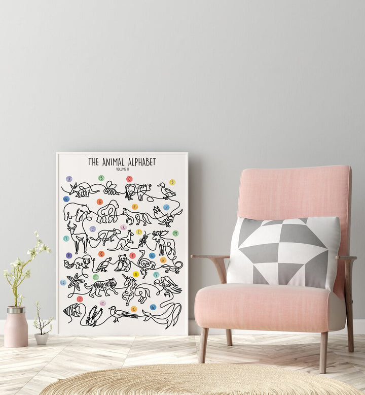 The Animal Alphabet Volume II by Hanna Lee Tidd Kids Room Paintings in White Plain Frame placed on the floor beside a chair