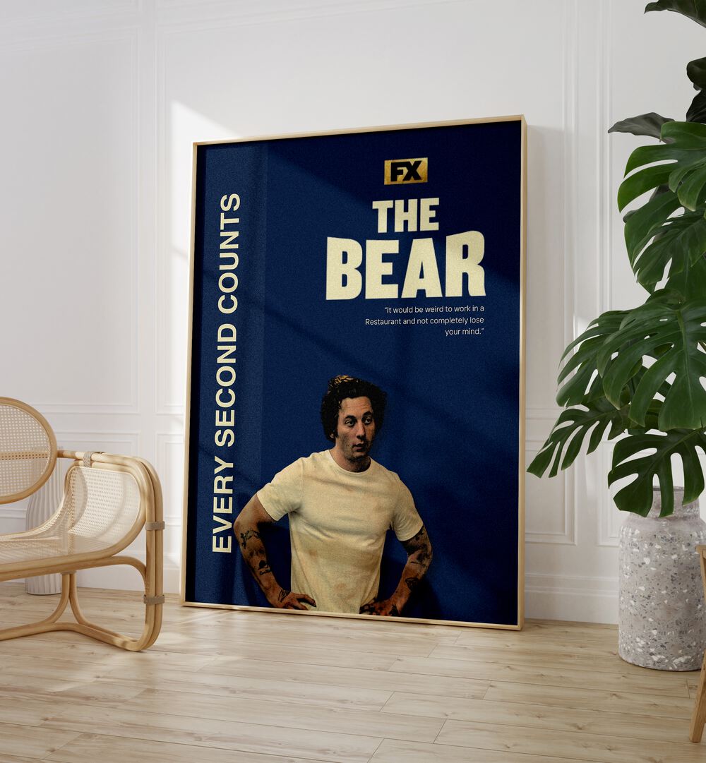 The Bear By Grishma Korjani Movie Posters in Oak Wood Plain Frame placed on a Wooden Floor near a White Colored Wall in the Living Room