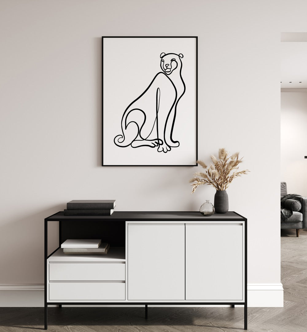 The Cheetah by Hanna Lee Tidd Line Art Paintings Line Art Prints in Black Plain Frame Frame placed on a wall behind a table