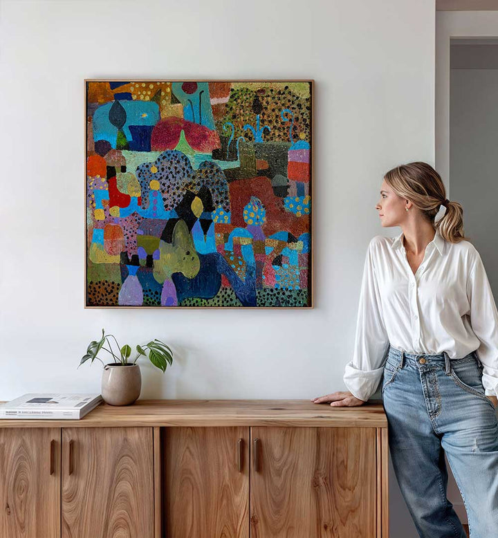 Woman viewing colorful abstract above wooden console, layered earth tones, THE VILLAGE , ABSTRACT PAINTINGS