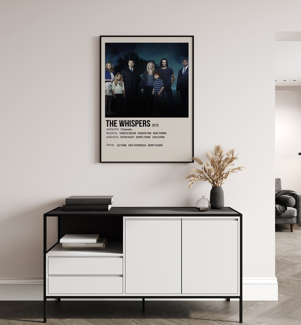 The Whispers 2015 Movie Posters in Black Plain Frame placed on a white wall behind a table