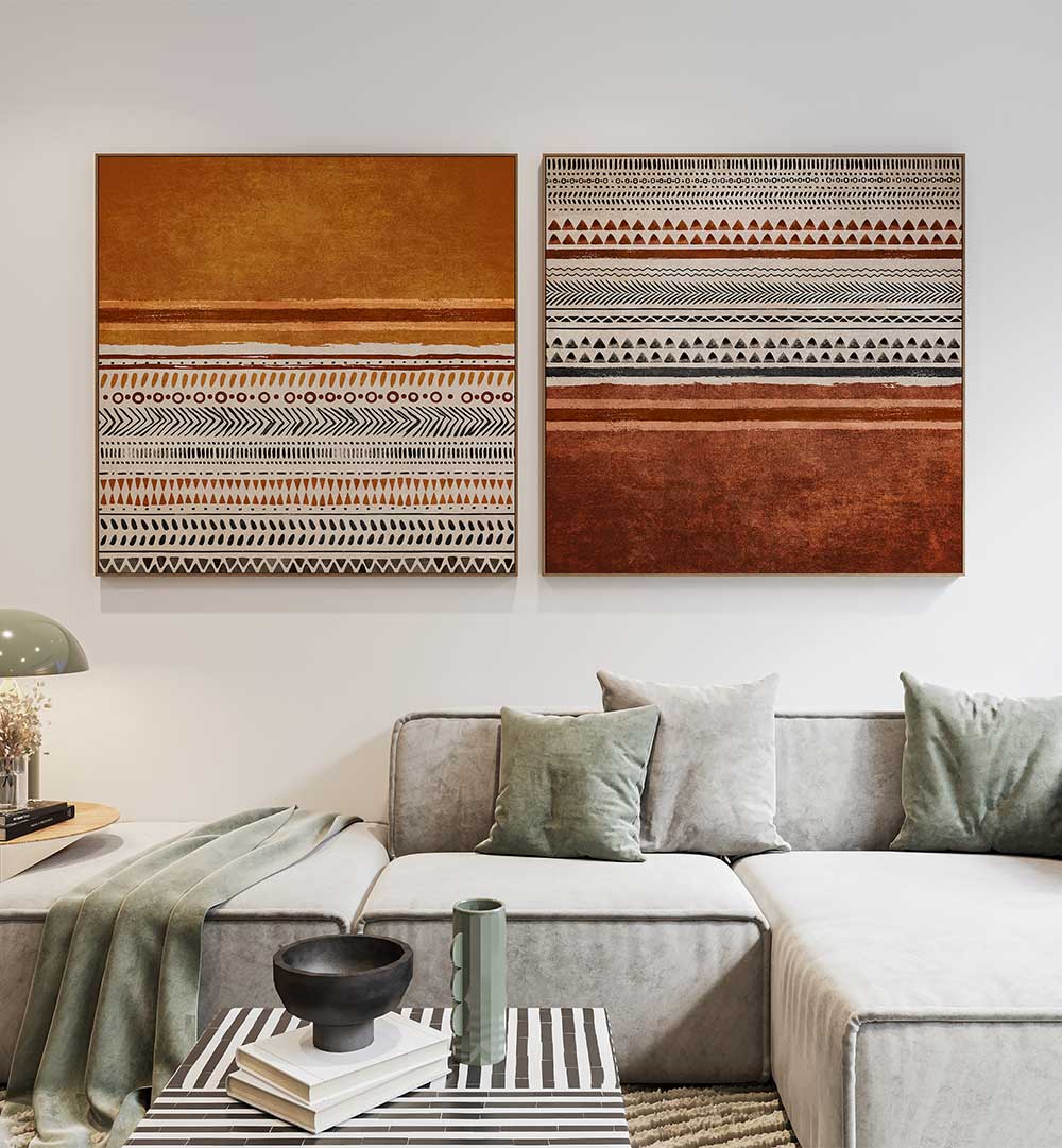 Two abstract art pieces on a wall above a sofa with decorative pillows.