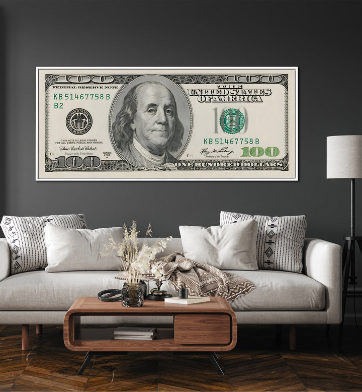 Us Dollar II Money Art Artwork in White Floater Frame Placed On a Dark Grey Wall Near a White Sofa in the Living Room