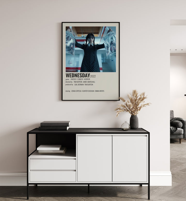 Wednesday 2022 Movie Posters in Black Plain Frame placed on a white wall behind a table