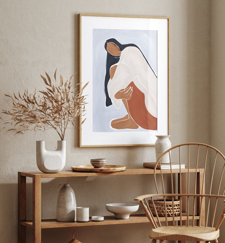 Woman Embracing Herself By Ivy Green Women Illustration Paintings in Oak Wood Frame With Mount on a beige wall above a table