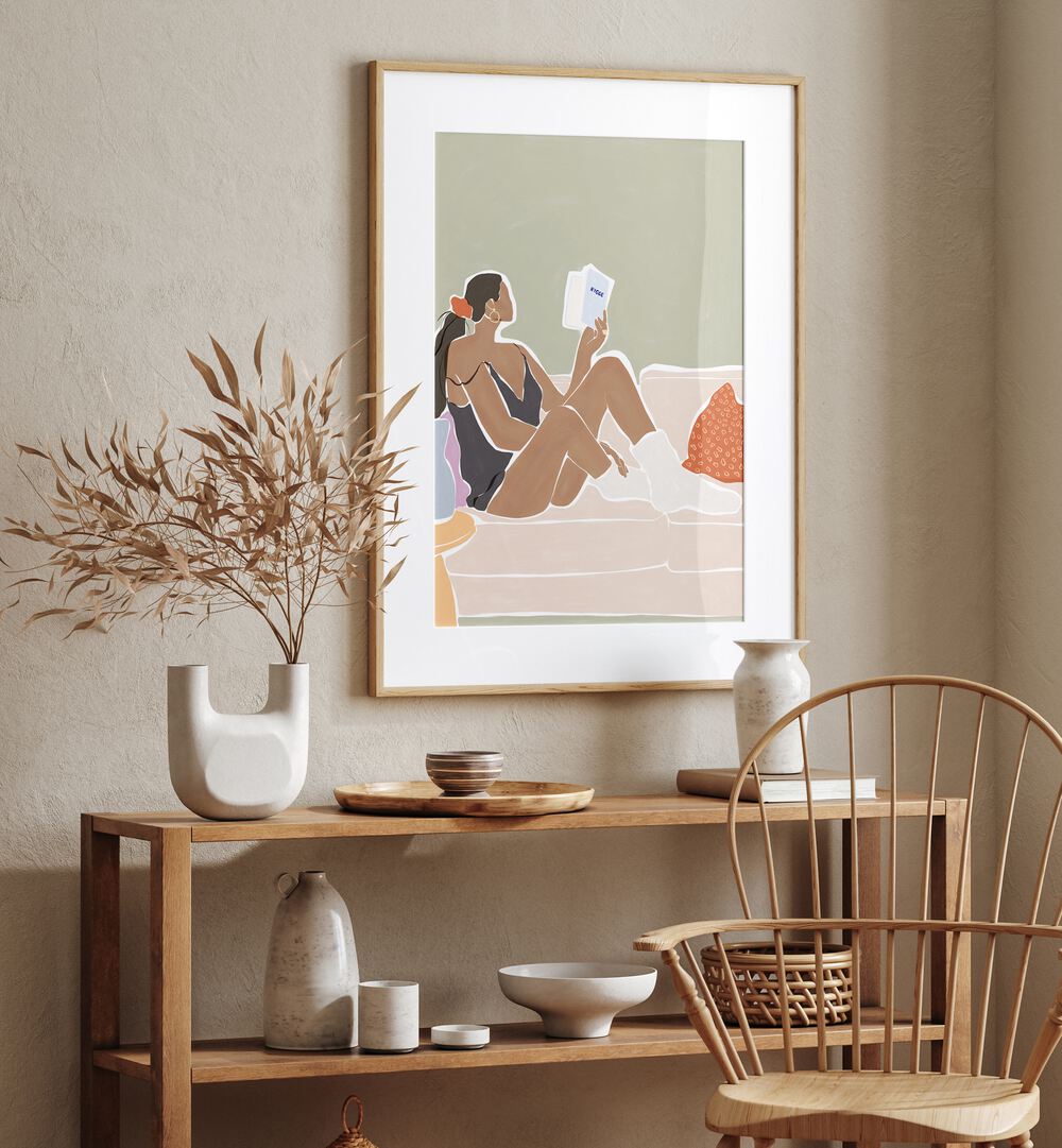 Women Reading a Book By Ivy Green Women Illustration Paintings in Oak Wood Frame With Mount on a beige wall above a table