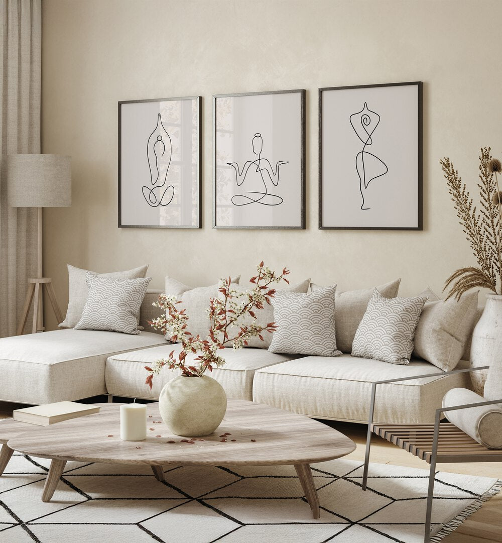 Yoga Line Art Set Set Of 3 Paintings in Black Plain Frame placed on a living room wall behind white sofa 