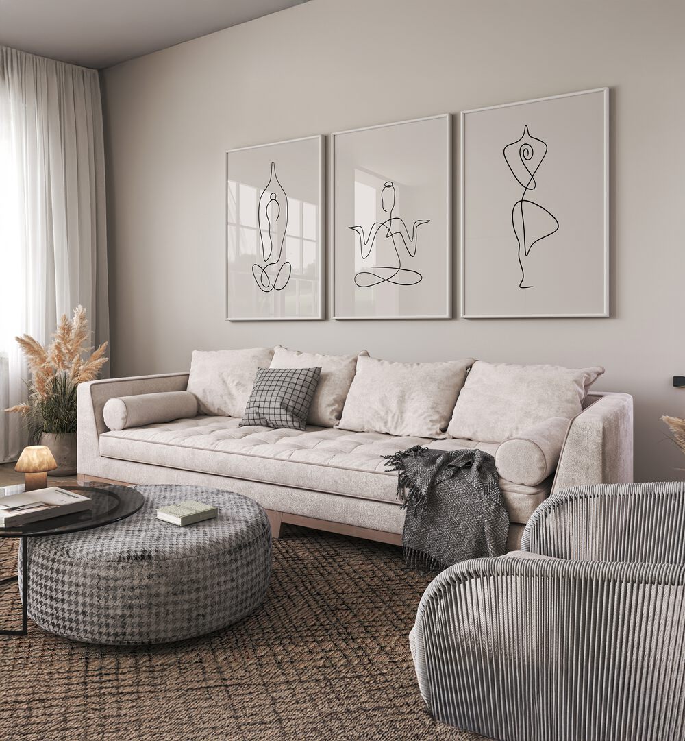 Yoga Line Art Set Set Of 3 Paintings in White Plain Frame placed on a living room wall behind a white sofa 