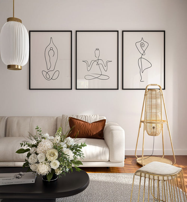 Yoga Line Art Set Set Of 3 Paintings in Black Plain Frame placed on a white wall behind a white sofa for living room