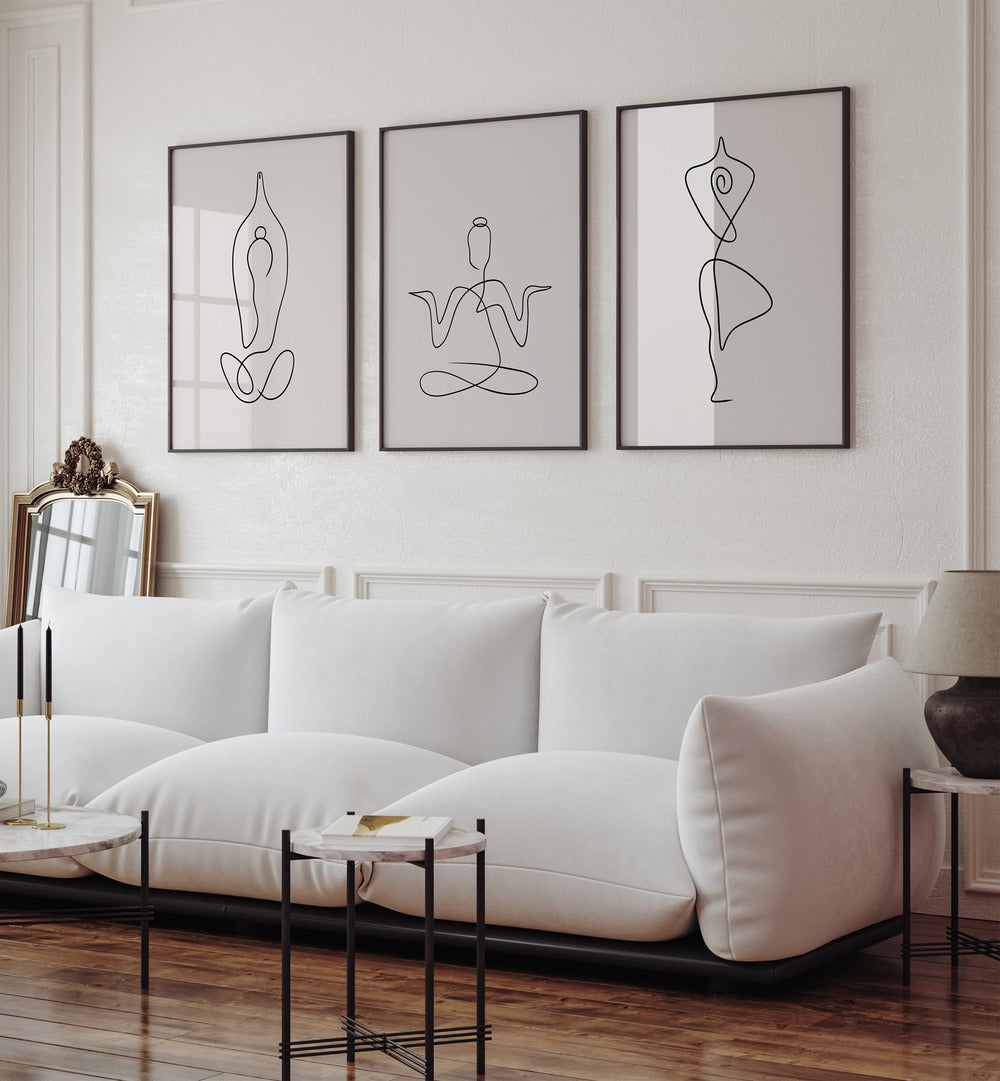 Yoga Line Art Set Set Of 3 Paintings in Black Plain Frame placed on a white wall behind a white sofa for living room