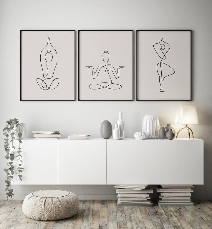 Yoga Line Art Set Set Of 3 Paintings in Black Plain Frame placed on a white wall behind a console table