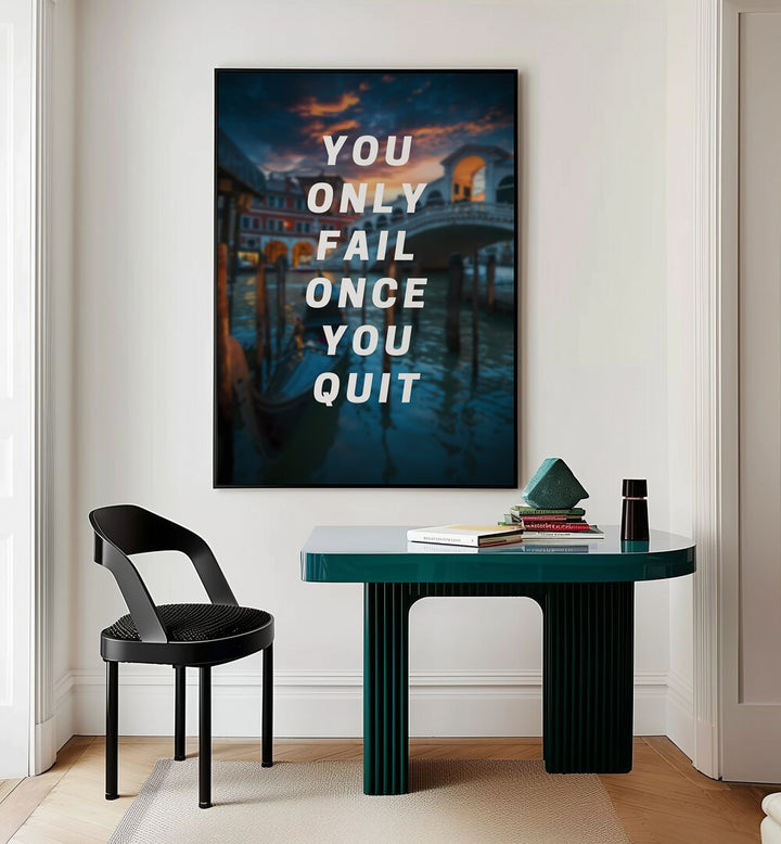 You Only Fail Once You Quit Quotes And Typography Posters in Black Plain Frame placed on a Cream Colored Wall near a Study Table in a Workspace in the Drawing Room