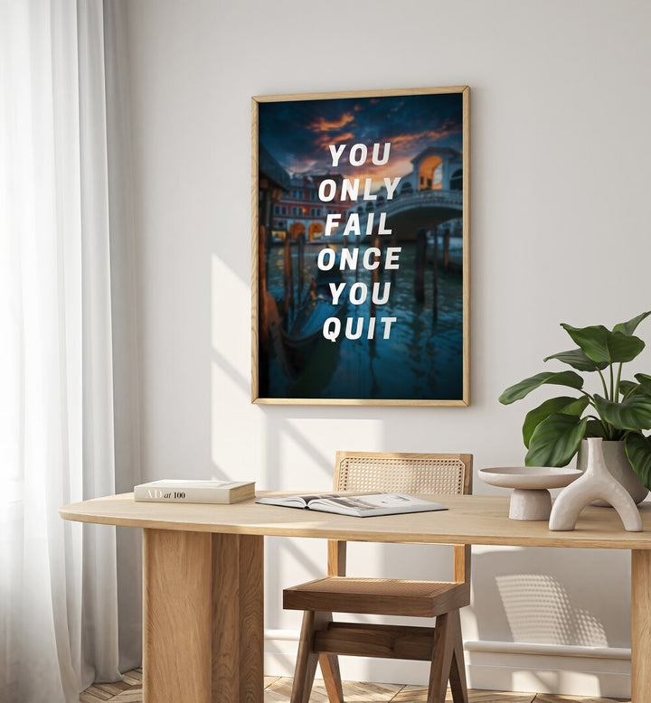 You Only Fail Once You Quit Quotes And Typography Posters in Oak Wood Plain Frame placed on a White  Colored Wall near a Study Table in a Workspace in the Drawing Room