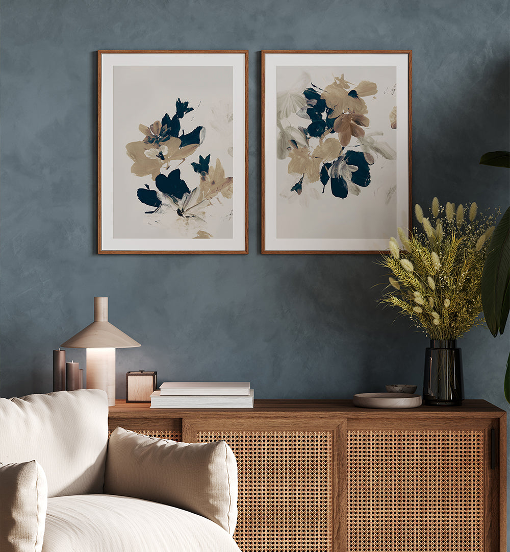 Two framed abstract floral artworks on a blue wall above a wooden cabinet with decorative items.